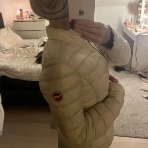 Beige dunjacka från Colmar - Säljer en snygg beige dunjacka från Colmar i mycket bra skick. Jackan har en dragkedja framtill och är perfekt för höst och vår. Den är långärmad och har en normal passform. Supermysig och stilren för kyligare dagar!