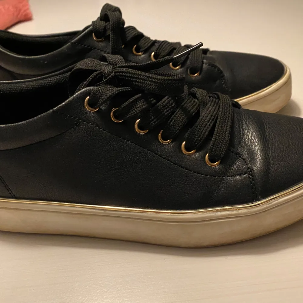 Säljer ett par svarta sneakers från miss Selfridge/ Anna Field  i bra skick. De har en stilren design med svarta snören och en vit sula. Perfekta för vardagsbruk och passar till det mesta i garderoben. Skorna är bekväma och har en klassisk look. Tunn silverkant. . Skor.