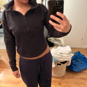 Svart croppad hoodie - Säljer en svart croppad hoodie med dragkedja. Perfekt för en avslappnad stil och passar bra till både träning och vardag. Den har långa ärmar och en hög krage som kan justeras med dragkedjan. Superbekväm och stilren. 