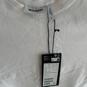 Vit croppad t-shirt från Weekday - Säljer en helt ny vit croppad t-shirt från Weekday. Den är i ett mjukt bomullsmaterial! Perfekt för sommardagar eller som en bas i garderoben. Aldrig använd, prislappen sitter kvar.