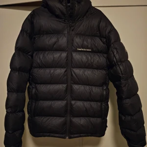 Svart dunjacka från Peak Performance - Säljer en svart dunjacka från Peak Performance i modellen Frost Down. Jackan är i mycket bra skick och perfekt för kalla vinterdagar. Den har en dragkedja framtill och är långärmad. Supervarm och stilren, perfekt för både vardag och äventyr! 🖤