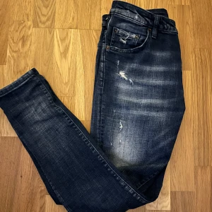 Mörkblå jeans från Dsquared2 - Säljer ett par snygga mörkblå jeans från Dsquared2 i storlek 44. De har otroligt feta slitningar och passar massor av olika klädstilar. Skicket är sjukt bra, knappast använda. Nypris 4000kr. Passar dig som är mellan 165-175. //L&FC