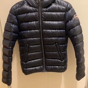 Mörkblå pufferjacka från Colmar - Säljer en snygg mörkblå pufferjacka från Colmar i mycket bra skick. Jackan har en dragkedja framtill och en mysig huva. Perfekt för kyliga dagar och håller dig varm och stilren. Passar både till vardags och lite finare tillfällen. 💙