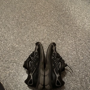 Svarta sneakers från Asics - Säljer ett par svarta Asics sneakers i mycket bra skick. De har en stilren design med snörning och är perfekta för träning eller vardagsbruk. Skorna har en bekväm passform och är gjorda i syntetmaterial för hållbarhet. Perfekta för dig som vill ha både stil och komfort!