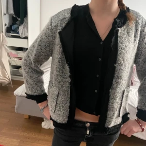 Grå kofta med svarta detaljer. - Säljer en snygg, unik grå kofta med svarta coola detaljer i mycket bra skick. Den är aldrig använd, enbart testad. Den har en cool textur, långa ärmar och en normal passform. Storlek M men modell är XS och passar, XS-M passar ish