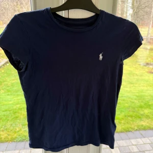 Mörkblå t-shirt från Ralph Lauren - Säljer en snygg mörkblå t-shirt från Ralph Lauren i bra skick. Den har en klassisk passform med korta ärmar. Perfekt för både vardag och avslappnade tillfällen.