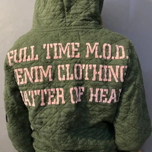 Grön quiltad kofta med tryck - Säljer en grön quiltad kofta med coola broderier och patches. Den har en dragkedja framtill och en mysig huva. Perfekt för höst och vår! Koftan är dekorerad med text och mönster i rosa och svart. Superunik och trendig! Kan mötas upp om man vill det inom Stockholm ( obs! Det är storlek s men är mer som en xs) 💗