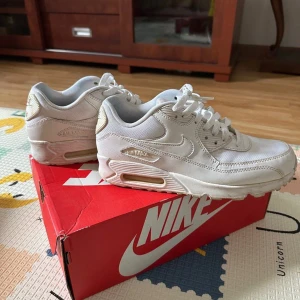 Vita Nike Air Max sneakers - Säljer ett par vita Nike Air Max sneakers i mycket bra skick. De har en klassisk design med synlig luftdämpning i sulan och är perfekta för både vardag och träning. Skorna har snörning och är gjorda i syntetmaterial för extra hållbarhet. Kommer i originalkartong.