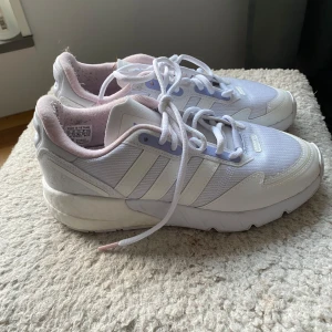 Vita sneakers från Adidas - Säljer ett par vita Adidas sneakers, använda men okej skick. Skorna har en liten smutsfläck på hälen