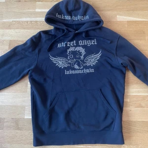 Svart rhinestone hoodie - Säljer en unik svart rhinestone hoodie från Lukamachain.  Hoodien har en unik design på luvan, perfekt för en avslappnad men ändå stilren look. Använd ett fåtal gånger och fortfarande i toppskick. Köptes för 800 kr, storlek S men passar även M.