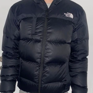Svart dunjacka från The North Face - Säljer en svart dunjacka från The North Face i mycket bra skick. Jackan är perfekt för kalla vinterdagar och har en dragkedja framtill. Den är långärmad och har en normal passform. Supermysig och varm, perfekt för vintern! ❄️