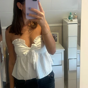 Vit axelbandslös topp  - Säljer en superfin vit axelbandslös topp med knyt framtill. Endast provad