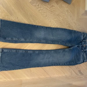 Blå jeans med broderade bakfickor - Säljer ett par snygga blå jeans i bra skick. De har en klassisk femficksdesign med coola broderade detaljer på bakfickorna. Perfekta för vardagsbruk och passar till det mesta. Sköna och stilrena!