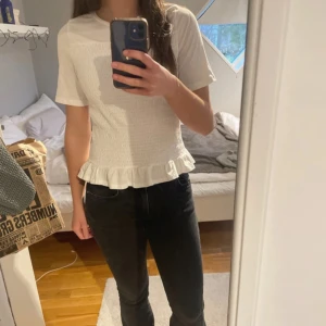 Vit topp med volangdetalj - Säljer en söt vit topp med korta ärmar och volangdetalj vid nederkanten. Den är endast använd 2 gånger, alltså i nyskick! Den är från Gina Young i storlek 170 men passar xs/s. Nypris 219💓