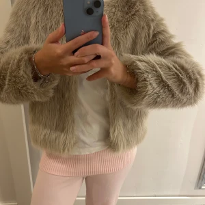 Beige pälsjacka - Säljer en beige pälsjacka. Jackan har en stilren design utan krage och långa ärmar. Den är i mycket bra skick och passar perfekt för höst och vinter. Strl 34