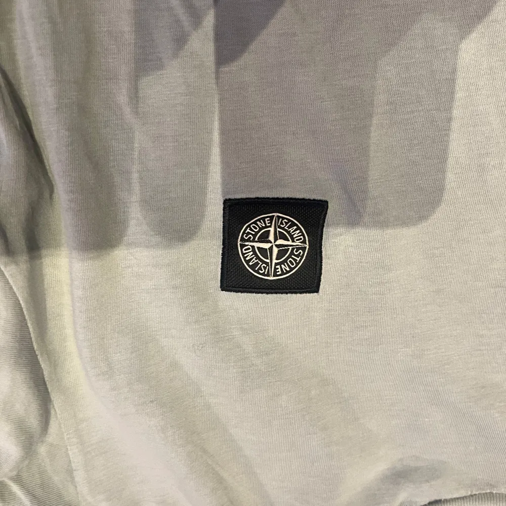 Säljer en stilren grå t-shirt från Stone Island Junior. Det finns ett litet hål på nedre delen av tröjan säljer därav lite billigare. Pris kan diskuteras. T-shirts.