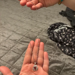 Silverhalsband med hjärtformad berlock ÄKTA SILVER - Ett elegant silverhalsband med en hjärtformad berlock. Berlocken har en vacker design med små detaljer som ger en romantisk känsla. Perfekt för speciella tillfällen eller som en fin present. Kedjan är tunn och smidig, vilket gör den bekväm att bära hela dagen. ÄKTA SILVER!