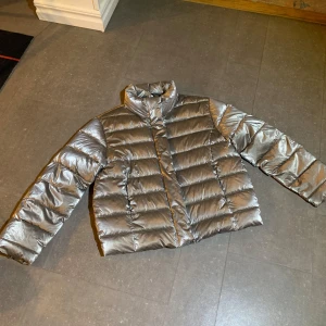 Silver pufferjacka från Zara - Säljer en snygg silverfärgad pufferjacka från Zara. Jackan har en glansig finish och är perfekt för kalla dagar. Den har långa ärmar och stängs med dragkedja. Perfekt för att sticka ut i vintermörkret! Helt som ny, aldrig använd! Köptes på rea för 370kr på Zara, det är en vinterjacka så den tål kyla! Tryck gärna på köp nu