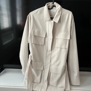 Beige jacka från Topshop - Säljer en snygg beige jacka från Topshop i storlek S. Jackan har en stilren design med långa ärmar och flera praktiska fickor framtill. Perfekt för vår och höst! 🧥uk 8