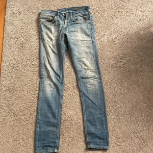 Dondup George  - Säljer ett par snygga blå slim jeans från Dondup med modell George i storlek 29. Skicket är 9/10 och nypris är 2500-3000 kr. De har en cool slitning och en klassisk femficksdesign. Beninnerlängd 80 cm och midjemått 37 cm. Passar dig om är ca 175 cm lång. Hör av dig ifall du har några frågor!