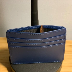 Blå plånbok  - Snygg och stilren blå plånbok med flera kortfack. Perfekt för att hålla ordning på dina kort och kontanter. Den är kompakt och lätt att bära med sig i fickan eller väskan. Perfekt för både vardag och fest!