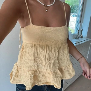 Gul topp med öppen rygg - Säljer en söt gul topp med tunna axelband och öppen rygg. 