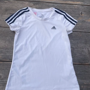 Vit t-shirt från Adidas - Säljer en vit tränings t-shirt från Adidas i storlek 152 för ändast 20 kr. Perfekt för träning eller vardagsbruk. 