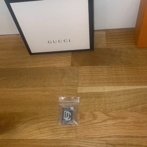 Silverfärgad ring med bokstavsdesign - Säljer en stilren och trendig silverplateräd dream chasers hängsmycke. Den har en unik design med en framträdande bokstavsdetalj. Perfekt accessoar för att ge din outfit en lyxig touch. Kommer i originalförpackning.