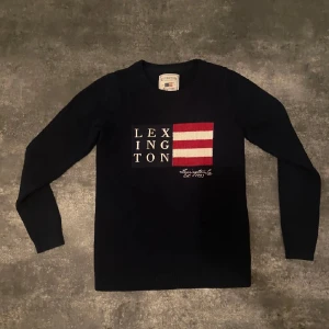 Mörkblå tröja från Lexington - Säljer en snygg mörkblå tröja från Lexington med ett coolt tryck på framsidan. Tröjan har långa ärmar och en ribbad krage ny pris 1200 mitt pris 450. Perfekt för höst och vinter, och den är i mycket bra skick. Passar både till vardags och lite finare tillfällen.