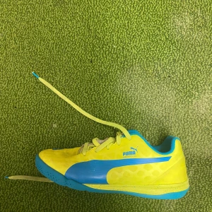 Gula och blå fotbollsskor från Puma - Säljer ett par coola fotbollsskor från Puma i gult och blått. Skorna har snörning och är i bra skick, perfekta för fotbollsträningen. De har en snygg design med Pumas logga på sidan och ovansidan.