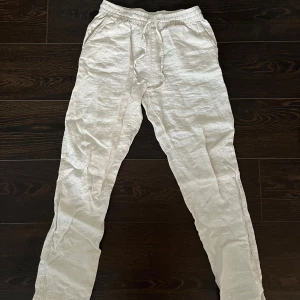 Ljusbeigea linnebyxor - Säljer ett par ljusbeigea linnebyxor i bra skick. De har en avslappnad passform med snörning i midjan för extra komfort. Perfekta för sommardagar eller en avslappnad stil. Passar både till stranden och vardags.