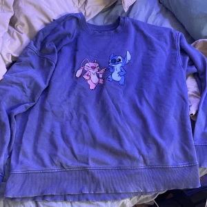 Blå tröja med Stitch och Angel från Primark - Säljer en superfin blå tröja från Primark med Stitch och Angel tryck på framsidan. Tröjan är i bra skick och perfekt för alla Disney-fans. Den har långa ärmar och är gjord i ett mjukt material som är skönt att ha på sig. Perfekt för mysiga dagar hemma eller en avslappnad dag ute.
