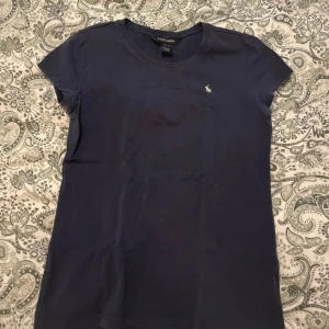 Mörkblå t-shirt från Ralph Lauren - Säljer en snygg mörkblå t-shirt från Ralph Lauren i storlek 12-14 (xs-s). 