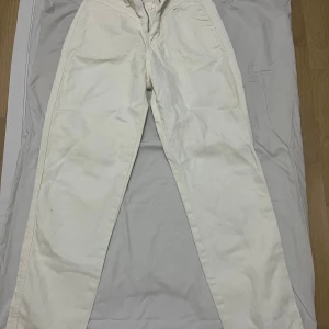 Vita byxor från NA-KD - Säljer ett par vita byxor från NA-KD i storlek 36. Byxorna har en klassisk design med dragkedja och knapp framtill. Perfekta för en stilren look oavsett tillfälle. De är i bra skick och redo för en ny ägare!