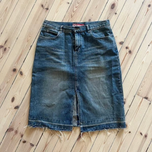 Jeanskjol med slits - Säljer en cool jeanskjol från Only. Den är i en klassisk blå denimfärg och har en snygg slits framtill och bak. Kjolen har en rå kant nertill som ger en avslappnad look. Perfekt för både vardag och fest!