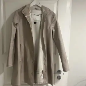 Beige regnjacka från Stutterheim. Några fläckar som säkert går bort med fläckborttagning. Skick 6/10