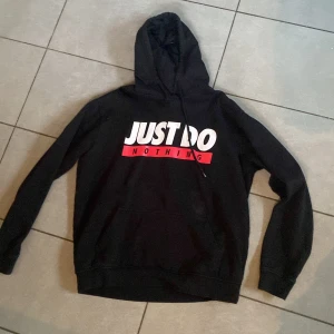 Svart hoodie från FSBN - Säljer en svart hoodie från FSBN i storlek XL. Den har  text på framsidan: 'JUST DO NOTHING' i vitt och rött. Perfekt för en chill dag eller när du bara vill ta det lugnt. Hoodien har långa ärmar och en klassisk passform. Den är gjord i ett mjukt och bekvämt material.