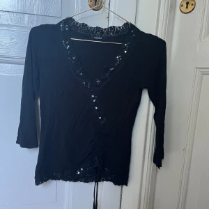 Trekvartsärmad topp med paljetter - Söt svart trekvartsärmad topp med paljetter och spets V-ringning Strl XS  Mycket fint skick