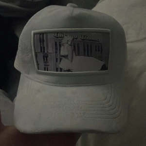 Vit keps med tryck - Säljer en vit keps med ett coolt tryck på framsidan. Kepsen har en justerbar baksida i mesh för bra ventilation. Perfekt för sommarens alla äventyr!