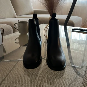 Svarta skinnstövletter från Gant - Säljer ett par stilrena svarta stövletter från Gant i skinn. Aldrig använda! De har en klassisk design med en dragflik baktill för enkel påtagning. Perfekta för både vardag och fest! Nypris 2000kr mitt pris är 1500kr