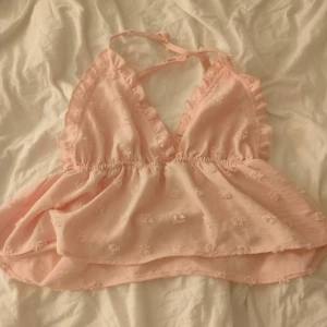 Linne - Söt rosa topp med volangdetaljer och broderade blommor. Den har smala axelband som korsas i ryggen och en v-ringad design. Perfekt för sommardagar eller en festlig kväll! Har klippt bort lappen men det är antagligen från shein. 