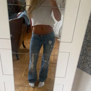 Lågmidjade utsvängda jeans - Säljer dehär assnygga lågmidjade utsvängda jeansen med så snygga slitningar. Midjemåttet är 38cm och innerbenslängden 83cm. Obs! De är slitna längst nere på jeansen men som inte syns så mycket (se sista bilden)💕