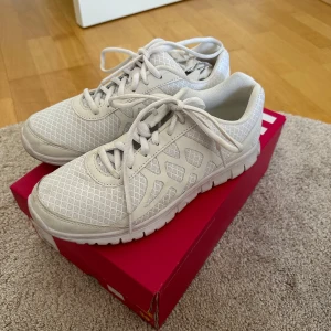 Vita sneakers i storlek 39 - Säljer ett par vita sneakers i storlek 39. De har en snygg och enkel design med snörning och ett mönstrat tyg. Perfekta för vardagsbruk och passar till det mesta. Skorna är i nyskick och kommer i originalkartong.