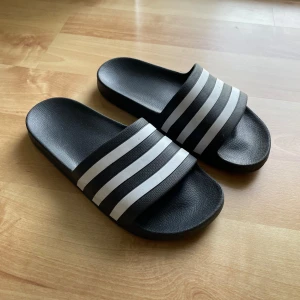 Adidas tofflor - Svarta badtofflor från adidas. I princip nyskick. Säljes pga har redan ett par likadana. Står storlek 39 tror jag men funkar på en 37-39 också, då jag har storlek 37 å de är lite för stora men passar ändå💓