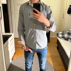 Burberry skjorta - Tjo! Säljer nu en otroligt eftertraktad och ovanlig burberry brit skjorta från 2016! Kan anvädas som mer Casual eller mer uppklätt. Färgen är en ljusblå med rutigt mönster. Skjortan är otroligt sparsamt använd och är i synnerligen bra skick! 