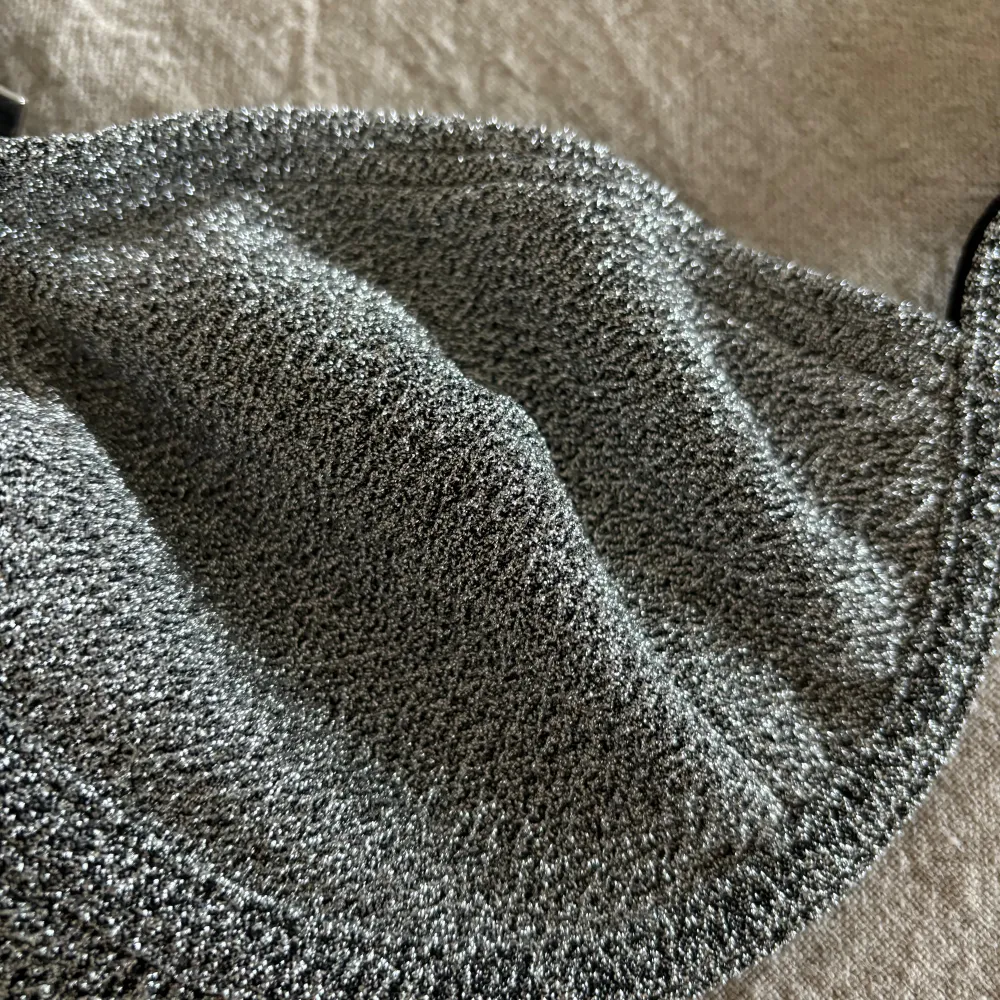 Säljer en superfin glittrig bikiniöverdel i silver. Den har en klassisk triangelmodell med smala axelband och en snygg glittrig yta som verkligen fångar ljuset. Perfekt för sommarens alla stranddagar eller poolpartyn! 💖. Muu.