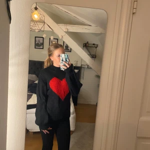 Stickad Tröja - Svart stickad tröja med rött glittrigt hjärta. Tröjan är aldrig använd fick den i julklapp för två år sedan. Det röda hjärtat är lite glittrigt. Jättevarm och skön till vintern. Skriv gärna med frågor🩷