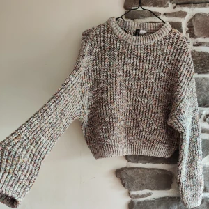 Flerfärgad stickad tröja från H&M - Säljer en supermysig flerfärgad stickad tröja från H&M:s Divided-kollektion. Tröjan har en härlig mix av färger som ger den ett unikt utseende. Den är långärmad och har en normal passform, perfekt för höst och vinter. Den är i nyskick och redo att värma dig under kyliga dagar!