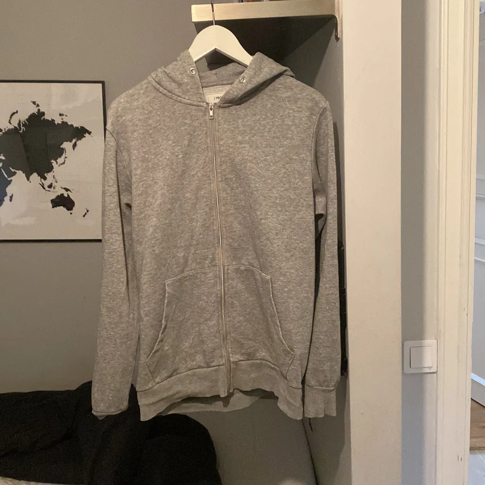 Säljer en grå hoodie från Produkt i storlek M. Den är supermjuk och perfekt för både höst och vinter. Hoodien har en dragkedja framtill och två praktiska fickor. Den är i bra skick och passar perfekt för en avslappnad stil. Perfekt för mysiga dagar hemma eller en chill dag ute!. Tröjor & Koftor.