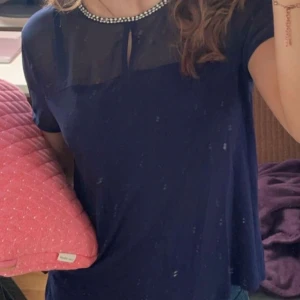 Mörkblå T-shirt  - Så snygg T-shirt från hm i mörkblått. Den har glittriga stenar vid halsen med en knapp i nacken och den har genomskinligt tyg ovanför bysten🩷 tyvärr har vissa stenar ramlat av. Spegeln som är smutsig